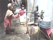 公共ポンプを使って水をくむ女性